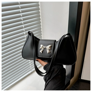 Detail of a black leather handbag featuring a polished silver metal bow buckle accent