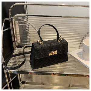 Detailed view of black woven texture leather bag with gold buckle on a modern shelf