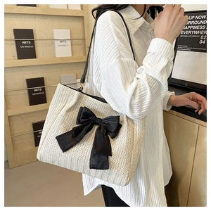 Sac cabas tissé beige orné d'un grand nœud noir avec bandoulière en cuir souple