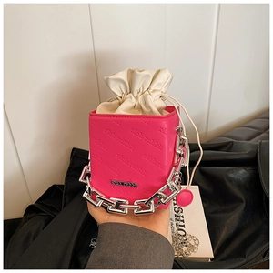 Detail of rose red bucket bag featuring rich rabbit embossed pattern and chunky silver chain