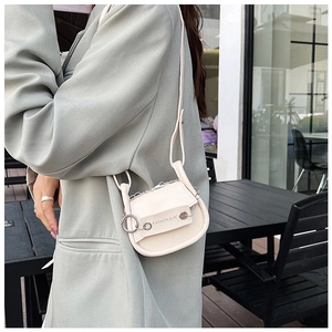 Detail einer cremeweißen Mini-Satteltasche mit Silberkette und FASHION & HC Text