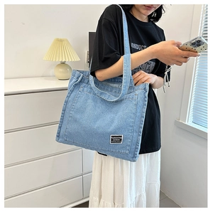 Detailed texture of light blue denim tote bag with fashion label and stylish stitching