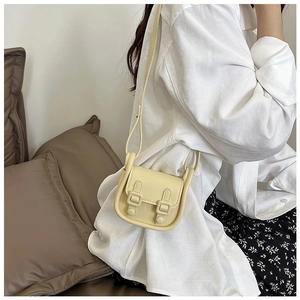 Détail d'un mini sac bandoulière beige clair avec deux boucles décoratives et fine lanière