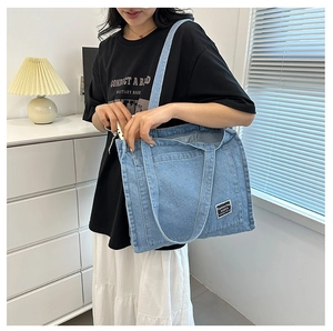 Detail of blue denim tote bag with functional front pocket and fashion label on the surface