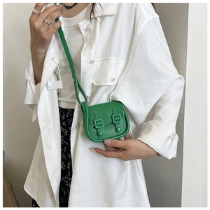 Détail d'un mini sac bandoulière vert vif à double boucles sur une chemise blanche