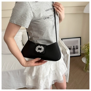 Détail d'un sac baguette en cuir noir avec une boucle carrée luxueuse ornée de strass