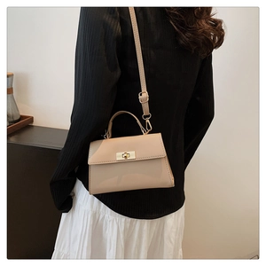Detail of a beige crossbody bag featuring a golden twist lock and adjustable strap
