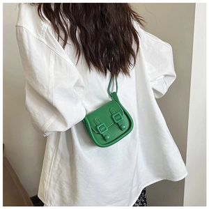 Gros plan d'un mini sac bandoulière vert herbe avec boucle en cuir rétro sur chemise blanche