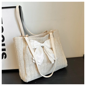 Détail d'un sac cabas tissé beige orné d'un grand nœud en soie blanche et fines bandoulières