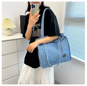 Close-up of light blue denim tote bag featuring vertical stitching and black brand label