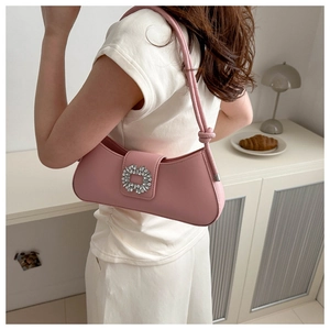 Sac baguette rose en cuir avec boucle en cristal porté à l'épaule par un mannequin