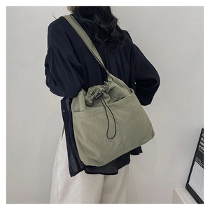 Detail view of sage green drawstring crossbody bag with side pocket and shoulder strap