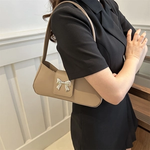 Beige faux leather underarm bag with a silver metallic bow buckle and slender shoulder strap