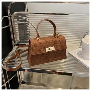 Detail of warm brown tote bag featuring a woven texture and golden rotating metal lock