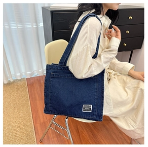 Close-up of a deep blue denim canvas tote bag with a white fashion label on the front