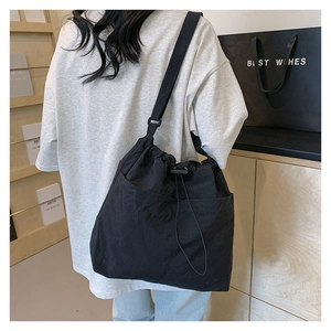 Detail showing the black nylon drawstring crossbody bag with large front utility pockets