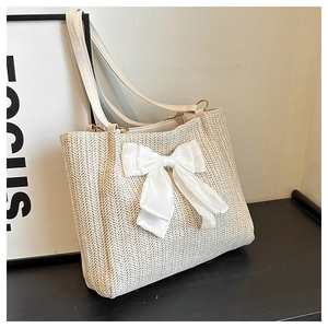 Vue détaillée du sac cabas en paille tressée avec un grand nœud décoratif en satin
