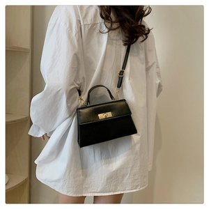 Classic black crossbody bag with gold metal buckle shown on a model in a casual setting