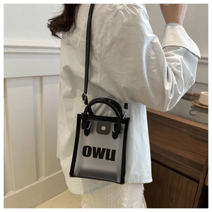 Détail du mini sac en PVC givré avec poignée en cuir noir et imprimé de lettres OWU