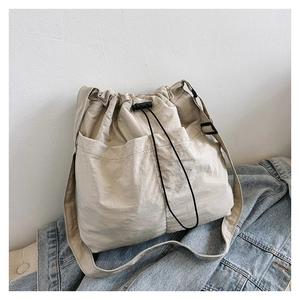 Detail view of nylon crossbody bag featuring front pockets and adjustable drawstrings