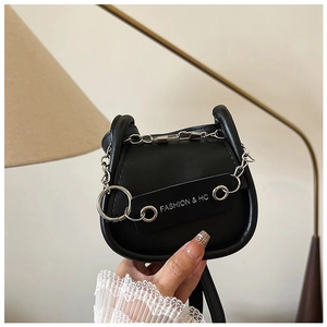 Detail der schwarzen Satteltasche mit Silberkette und Fashion-HC-Label in der Hand