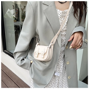 Petit sac bandoulière crème chic porté avec une tenue de printemps élégante