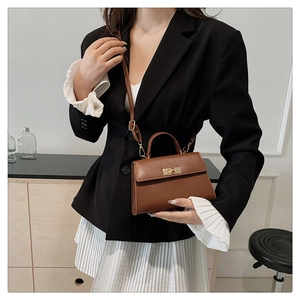 Brown leather crossbody bag detail with golden square lock and adjustable shoulder strap