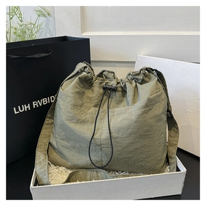 Detail of grey-green nylon drawstring bag with adjustable strap in gift packaging
