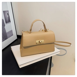 Detail of elegant beige crossbody square bag with metallic rotating clasp and leather handle