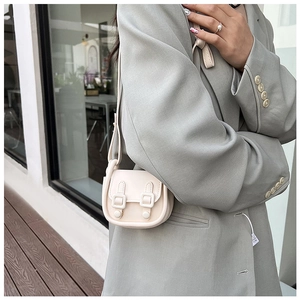 Petit sac à bandoulière crème chic porté avec un blazer vert sauge tendance