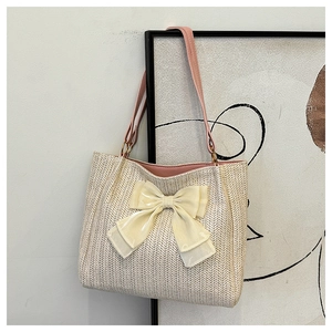 Détail d'un grand sac cabas en paille avec nœud en soie et anses en cuir rose