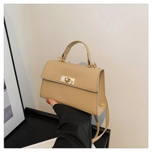 Detail of a beige small square bag with golden twist lock and neat stitching craft