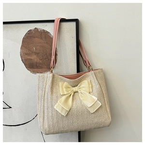 Détail du sac fourre-tout en paille blanche avec grand nœud en satin et anses en cuir rose