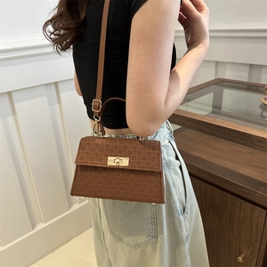 Brown woven texture crossbody handbag with gold clasp shown on a fashion model