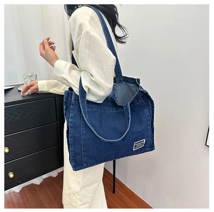 Deep blue denim tote bag detail showing heavy washed texture and branded cloth label