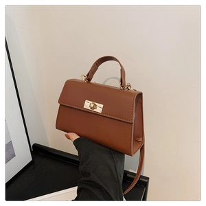 Detailed view of brown faux leather crossbody bag with golden metal turn-lock closure