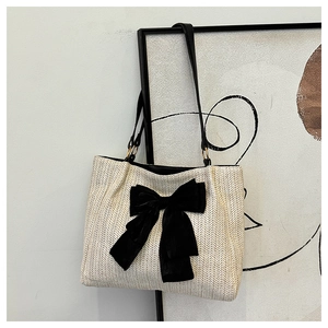 Texture détaillée du sac cabas en paille ivoire avec un grand nœud en velours noir