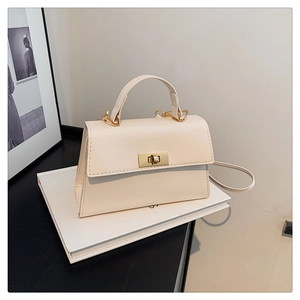 Detail view of cream white leather crossbody bag featuring an elegant gold metal turn-lock