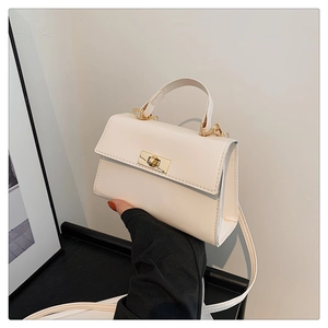 Detail of creamy white crossbody bag showing golden square twist lock and leather texture