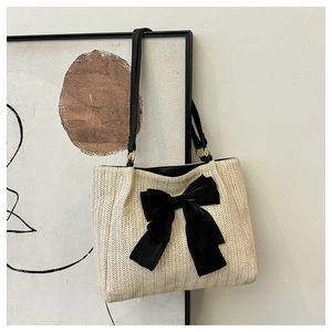 Détail du sac cabas en paille crème avec un grand nœud en velours noir et anneaux dorés