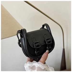 Gros plan sur le mini sac à rabat noir avec détails de boucles à double sangle vintage