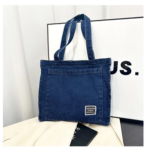 Detail shot of the dark blue denim tote bag showing twill texture and logo patch