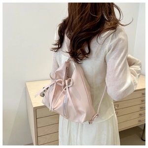 Détail d'un sac à dos rose pâle avec nœuds et fermetures éclair sur un mannequin