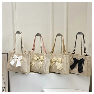 Gros plan de sacs cabas en paille avec grands nœuds en blanc, rose, beige et noir élégant