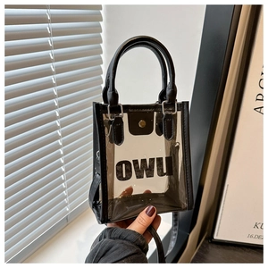 Détail d'un sac cabas en PVC transparent avec bordures en cuir noir et logo OWU