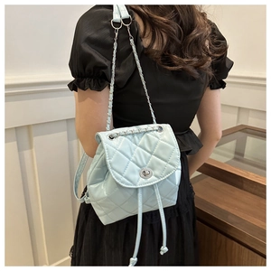 Detail of light blue quilted mini backpack with silver chain strap and twist lock closure