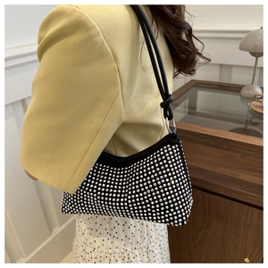 Detail of a chic black underarm bag with sparkling silver rhinestones on a yellow blazer