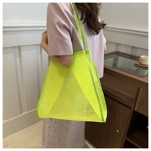 Bolso tote de malla verde neón al hombro en un ambiente de estilo minimalista