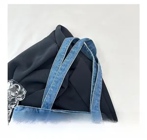 Close-up of wide denim shoulder straps with dark reinforced stitching on blue tote bag