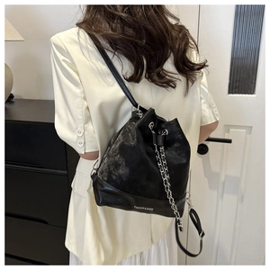 Detail der schwarzen Beuteltasche mit Kettenzug und FASHION & BAGS Logo auf Wildlederoptik